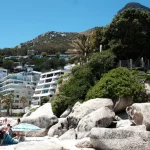 man in blue shirt sitting on rock near green trees during daytime